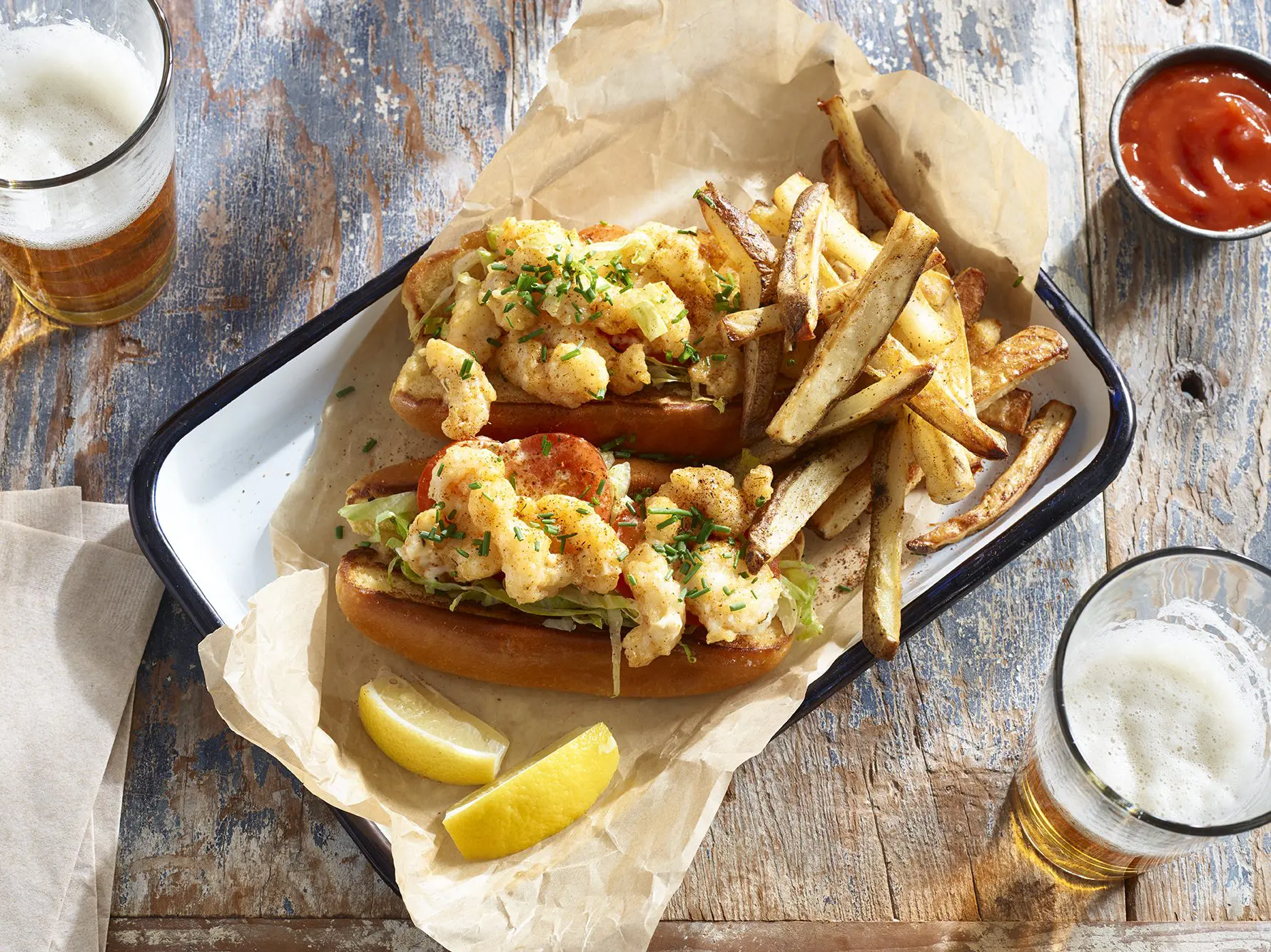 New England Shrimp Po' Boy with fries and beer on a wooden table