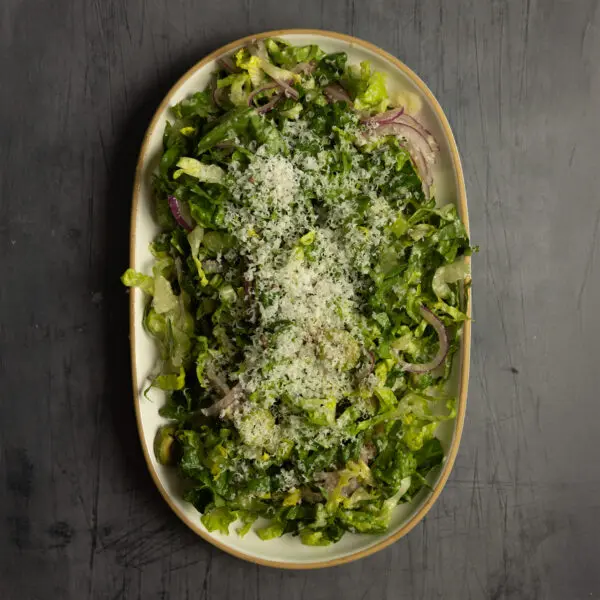 Overhead view of a large platter of Parmesan Chopped Salad served over a textured charcoal tabletop.