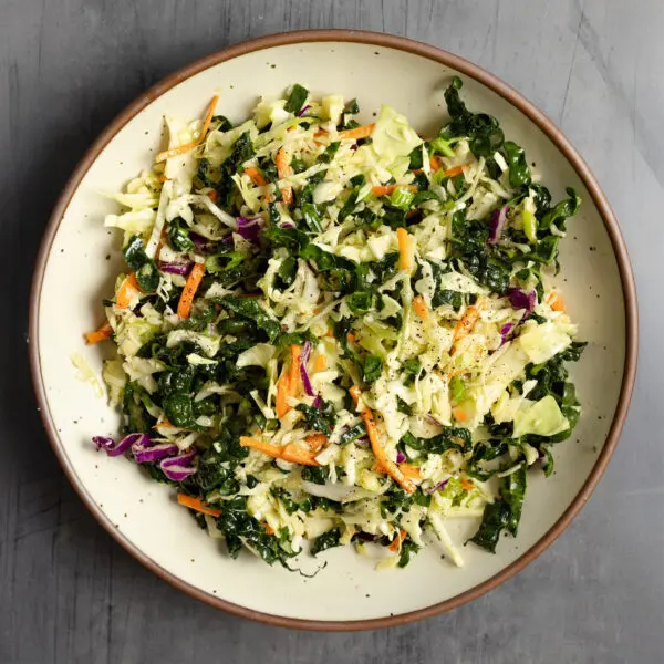 Overhead view of white ceramic bowl filled with crunchy kale slaw.