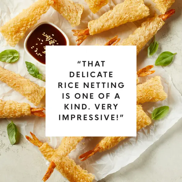 Overhead view of crispy wrapped shrimp with white box text overlay that reads "That delicate rice netting is one of a kind. Very impressive!"
