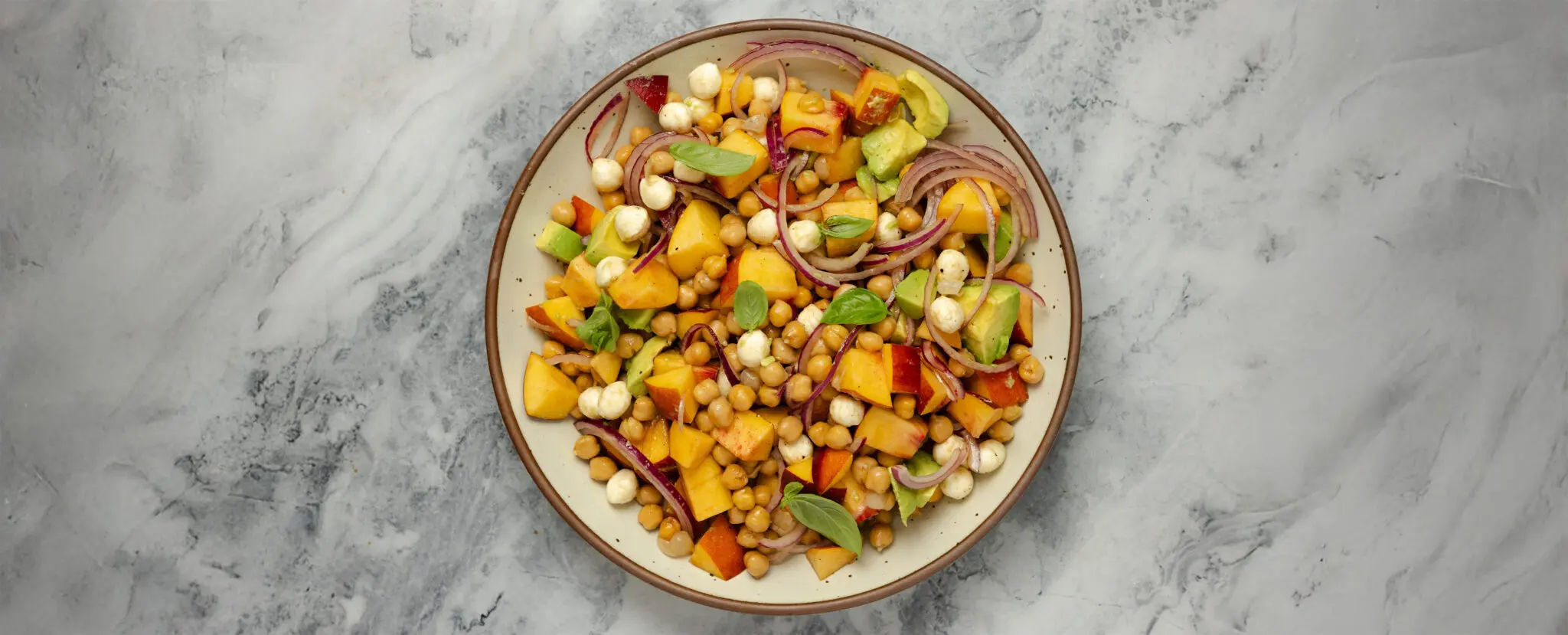 Overhead view of a white ceramic plate filled with a Summer Peach Salad.