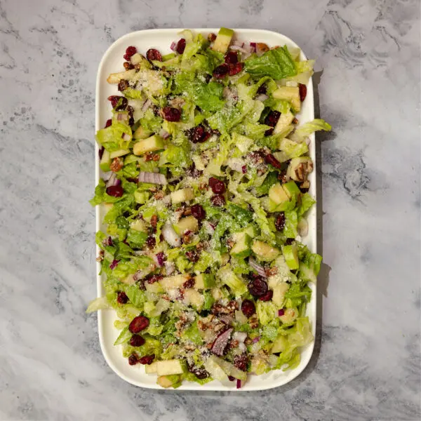 Overhead view of a large rectangular platter of Autumn Chopped Salad, served over a marble tabletop.