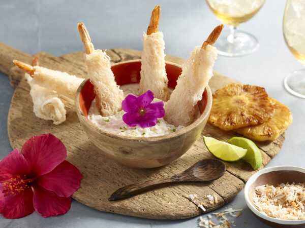Island Crispy Wrap Shrimp in a bowl of sauce on a wooden board with fresh flowers