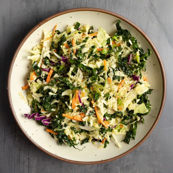 Overhead view of white ceramic bowl filled with crunchy kale slaw.